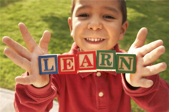 young boy holding blocks that spell out LEARN